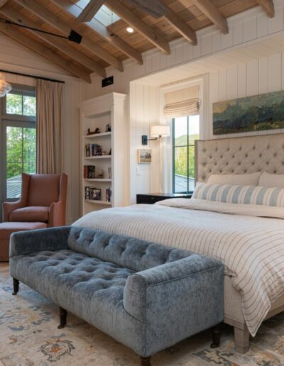 Master bedroom in a remodeled house with energy-efficient features, built by a luxury home builder near Asheville, North Carolina, incorporating original farmhouse aspects, locally milled wood, exposed beams, and natural elements.